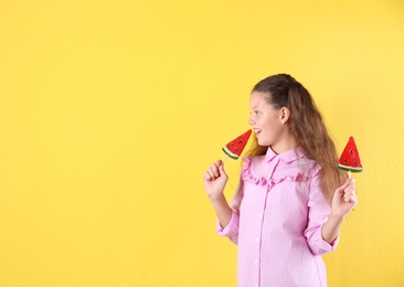 Photo of Little girl with candies on color background. Space for text