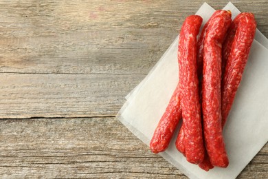 Photo of Thin dry smoked sausages on old wooden table, top view. Space for text