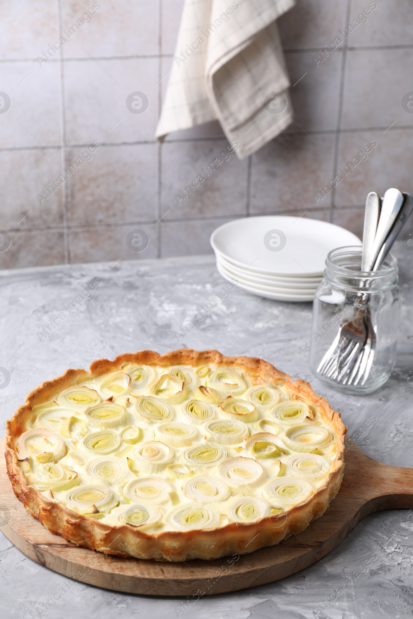 Photo of Freshly baked leek pie, forks and plates on grey textured table
