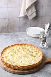 Photo of Freshly baked leek pie, forks and plates on grey textured table