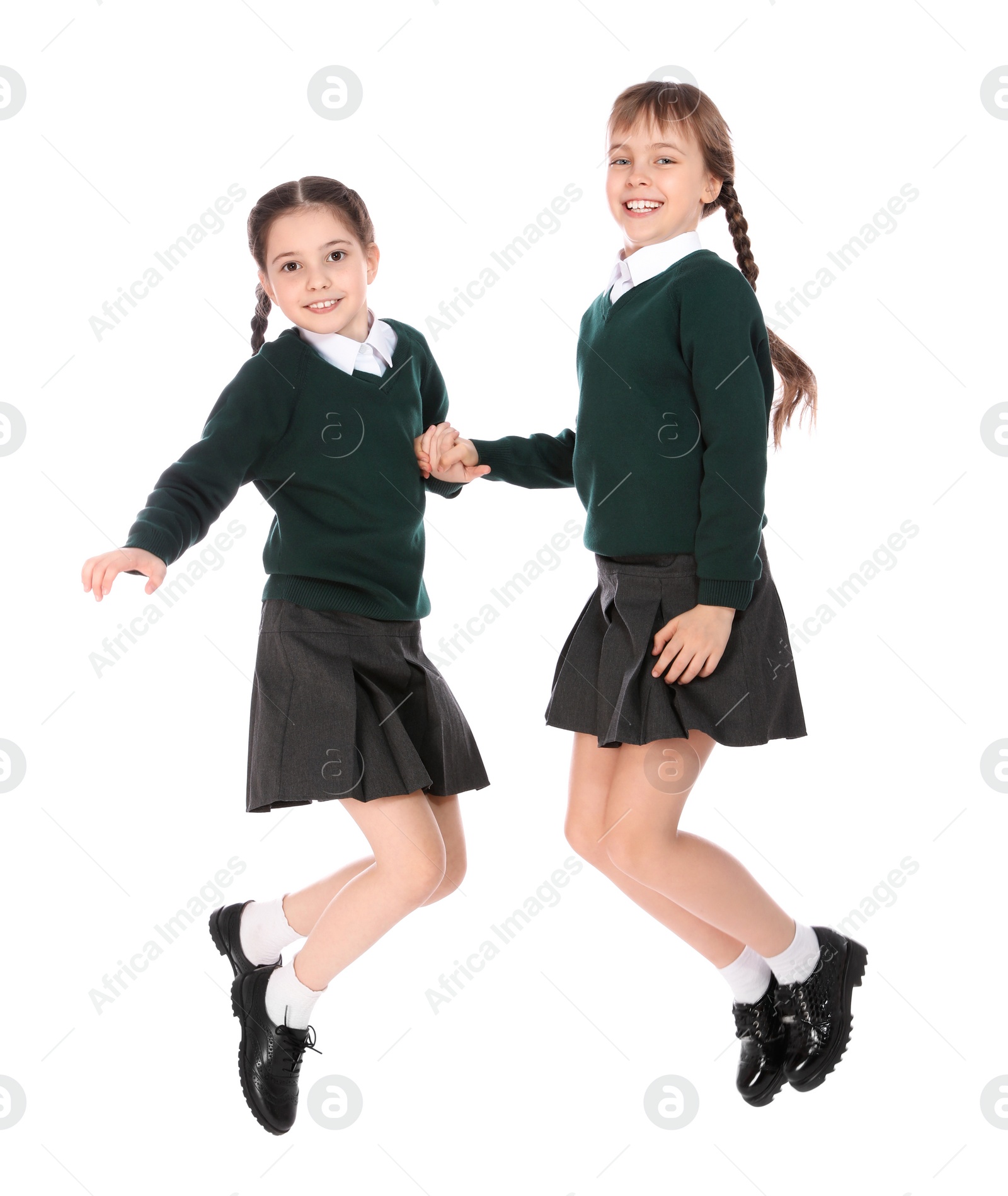 Photo of Cute girls in school uniform jumping on white background