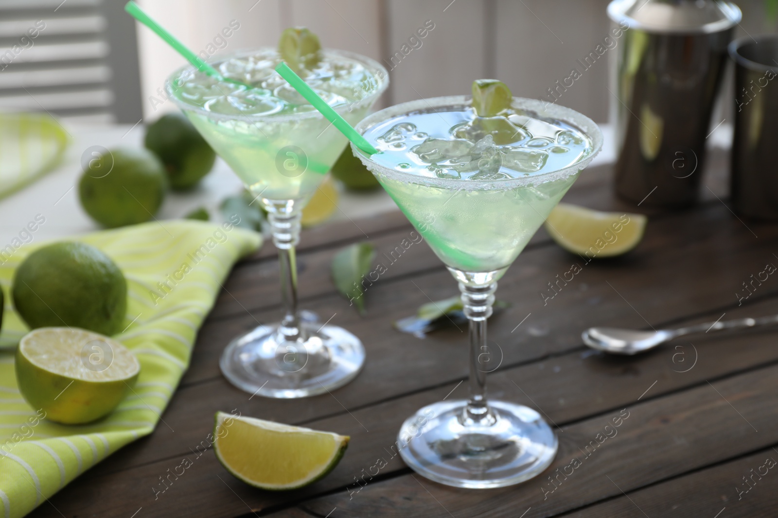 Photo of Delicious Margarita cocktail in glasses and lime on wooden table, closeup