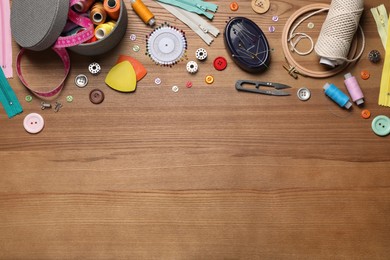 Photo of Flat lay composition with different sewing accessories on wooden background. Space for text