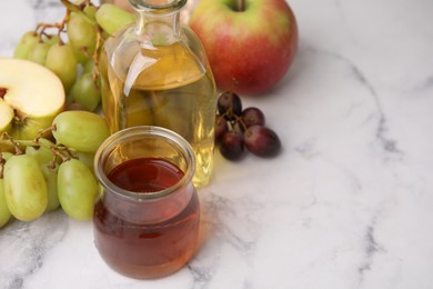 Photo of Different types of vinegar and ingredients on light marble table, closeup. Space for text