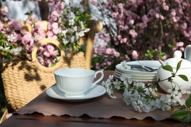 Photo of Beautiful spring flowers on table served for tea drinking in garden