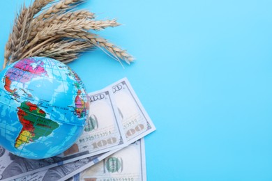 Import and export concept. Globe, ears of wheat and banknotes on light blue background, flat lay. Space for text