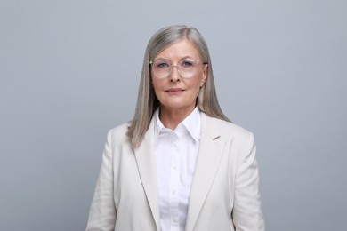 Portrait of beautiful senior woman in glasses on grey background