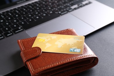 Photo of Credit card, laptop and leather wallet on grey table