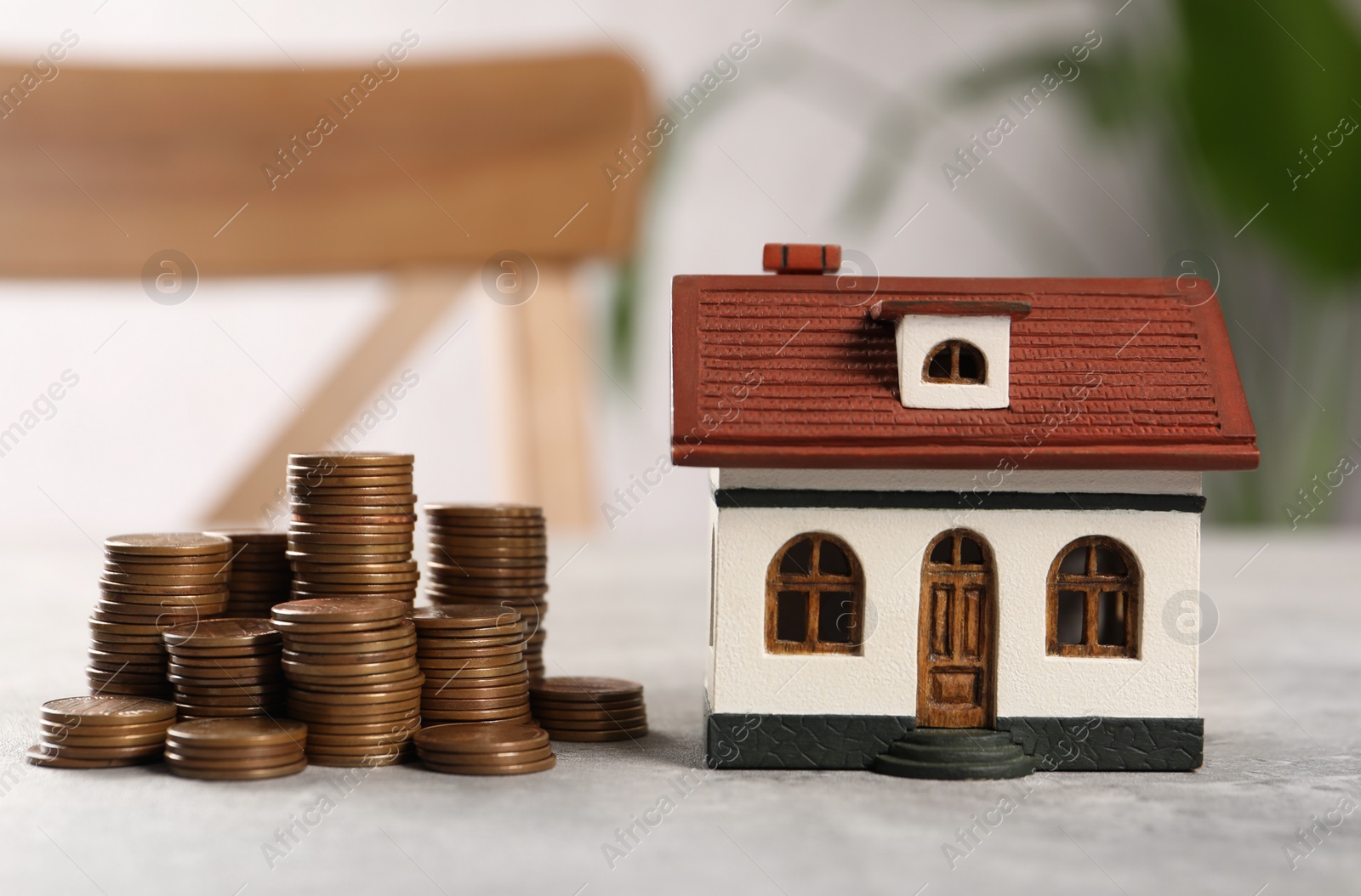 Photo of House model and stacked coins on grey table indoors, closeup