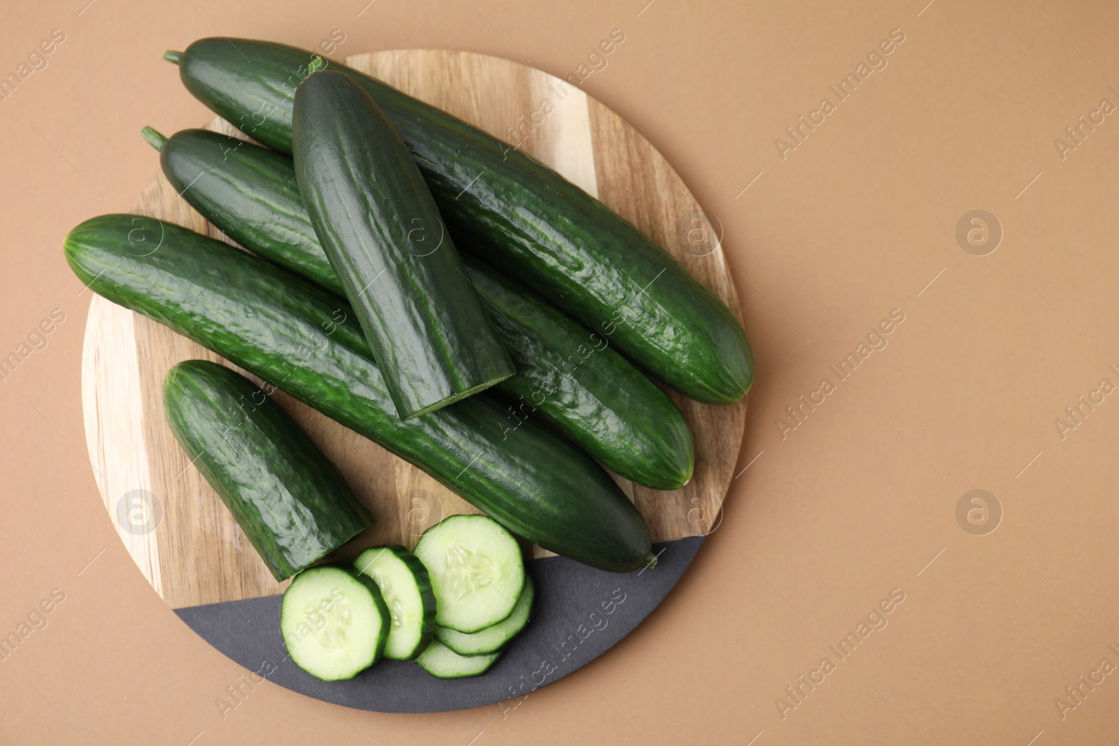 Photo of Fresh cucumbers on beige background, top view. Space for text