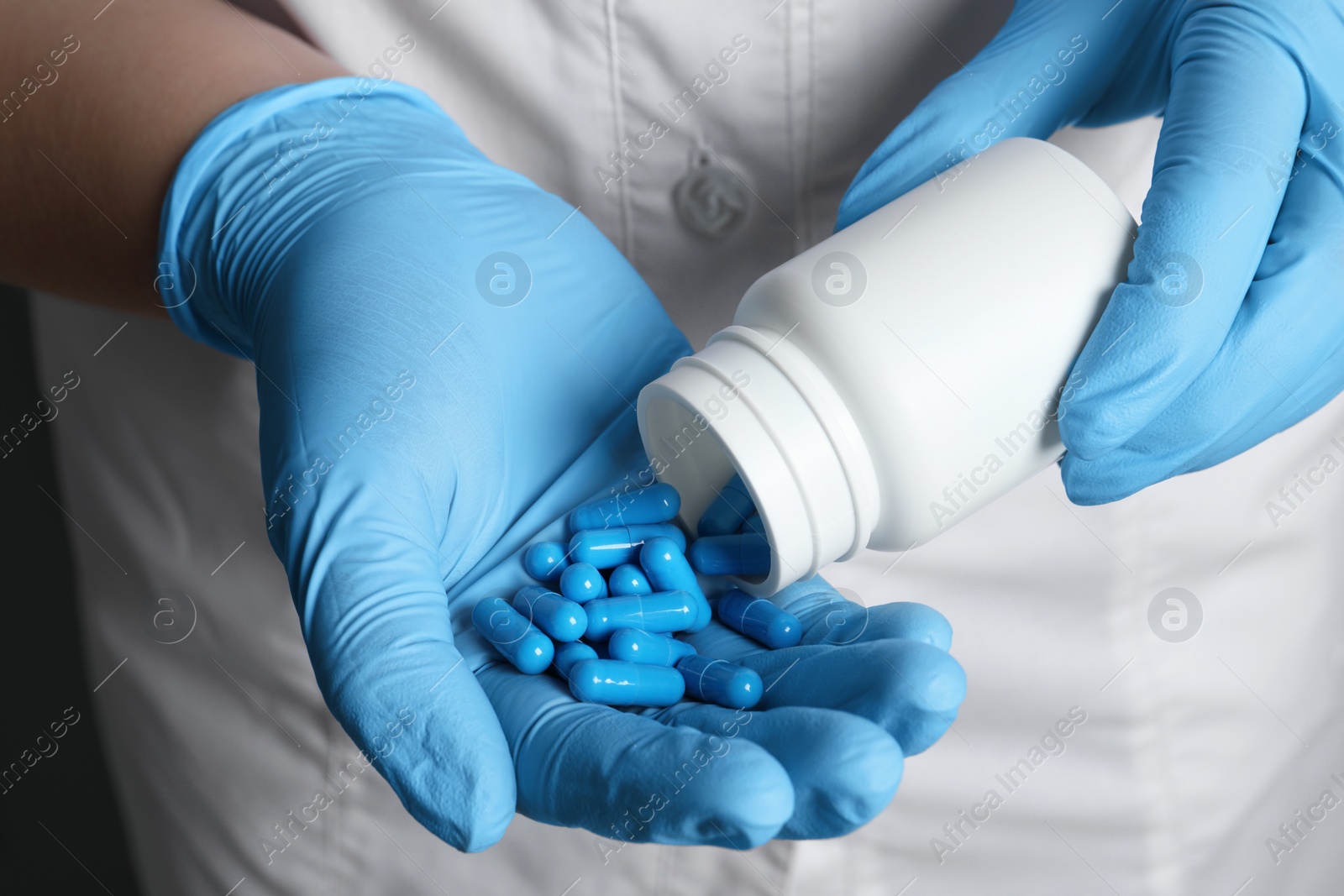 Photo of Doctor pouring pills from bottle onto hand, closeup view