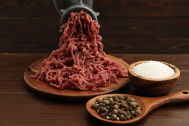 Photo of Meat grinder with beef mince and spices on wooden table