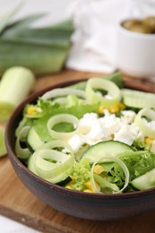 Bowl of tasty salad with leek and cheese on table, closeup