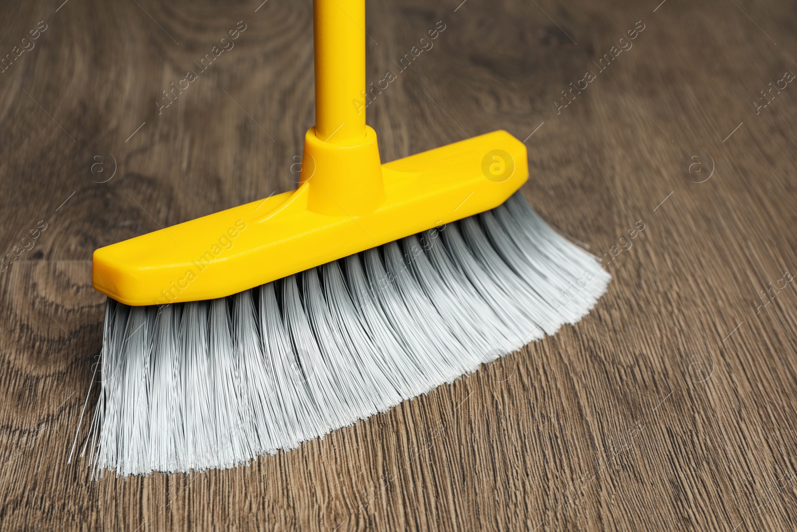 Photo of Sweeping wooden floor with plastic broom, closeup