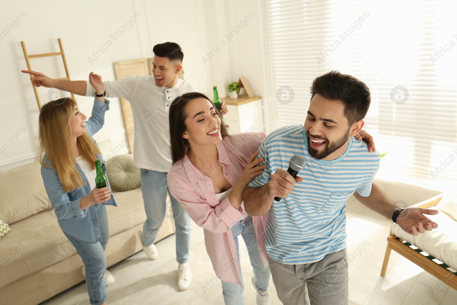 Photo of Young man singing karaoke with friends at home