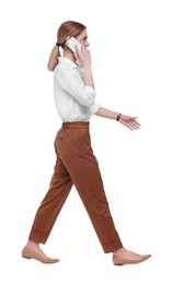 Photo of Beautiful businesswoman talking on smartphone while walking against white background