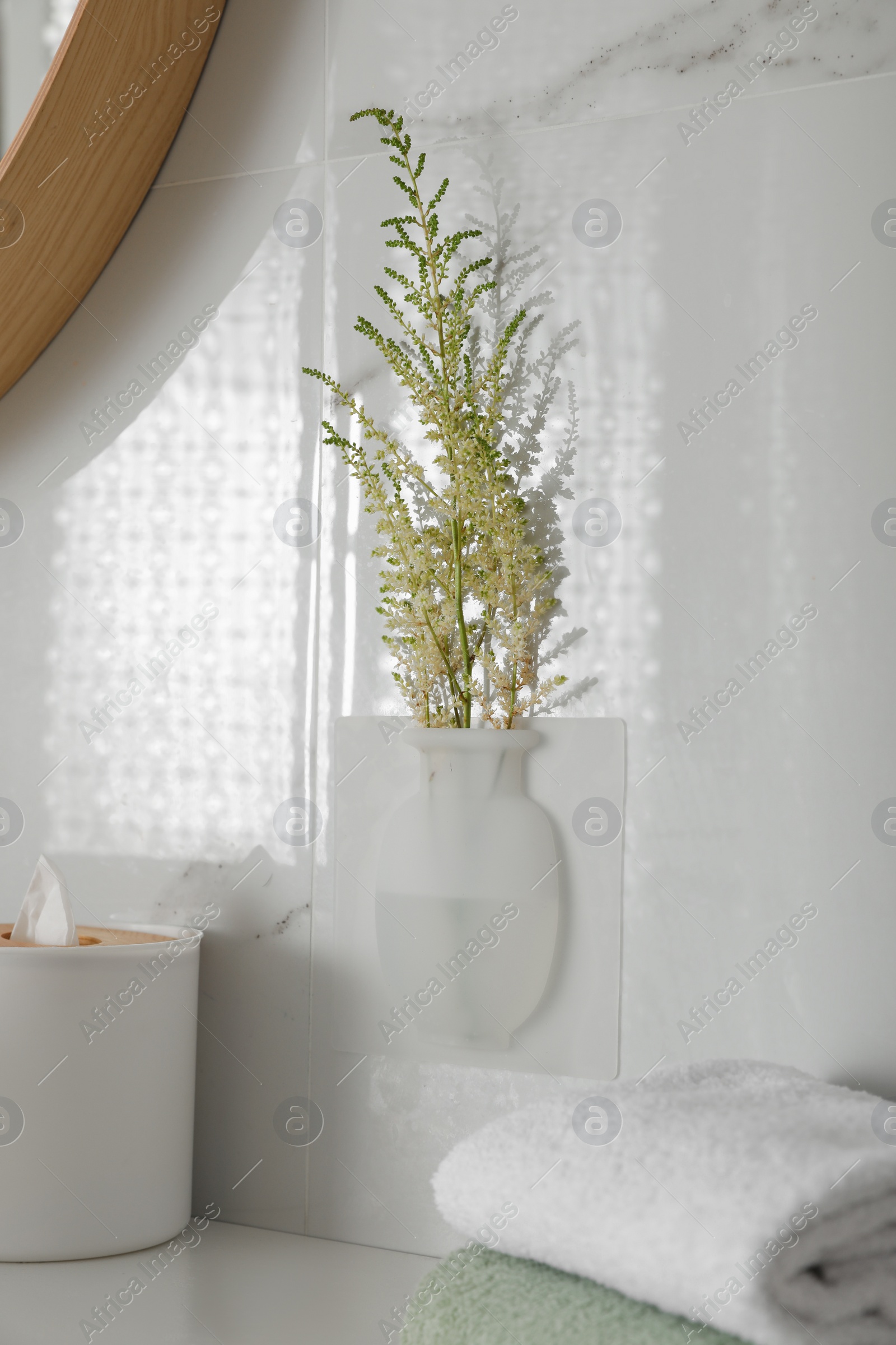 Photo of Silicone vase with flowers on white marble wall over countertop in bathroom