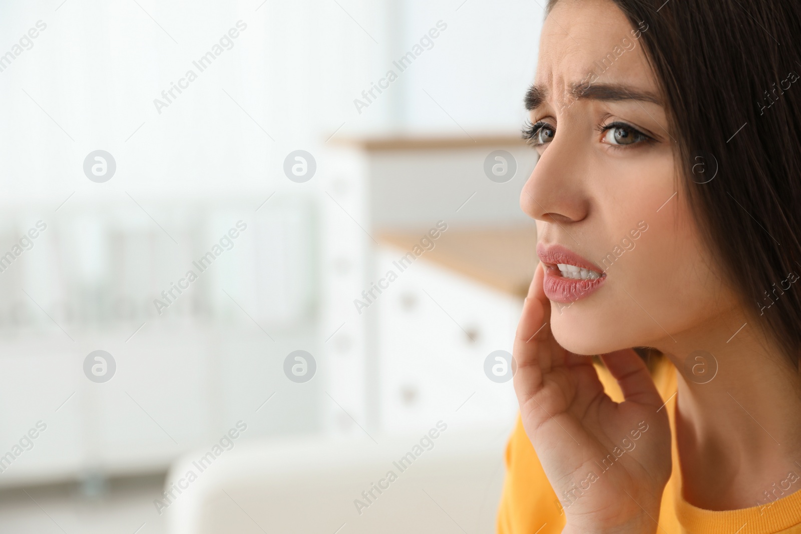 Photo of Young woman suffering from strong tooth pain at home, space for text