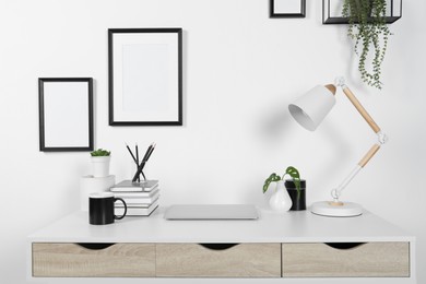 Photo of Home workplace. Laptop, lamp and stationery on white wooden desk