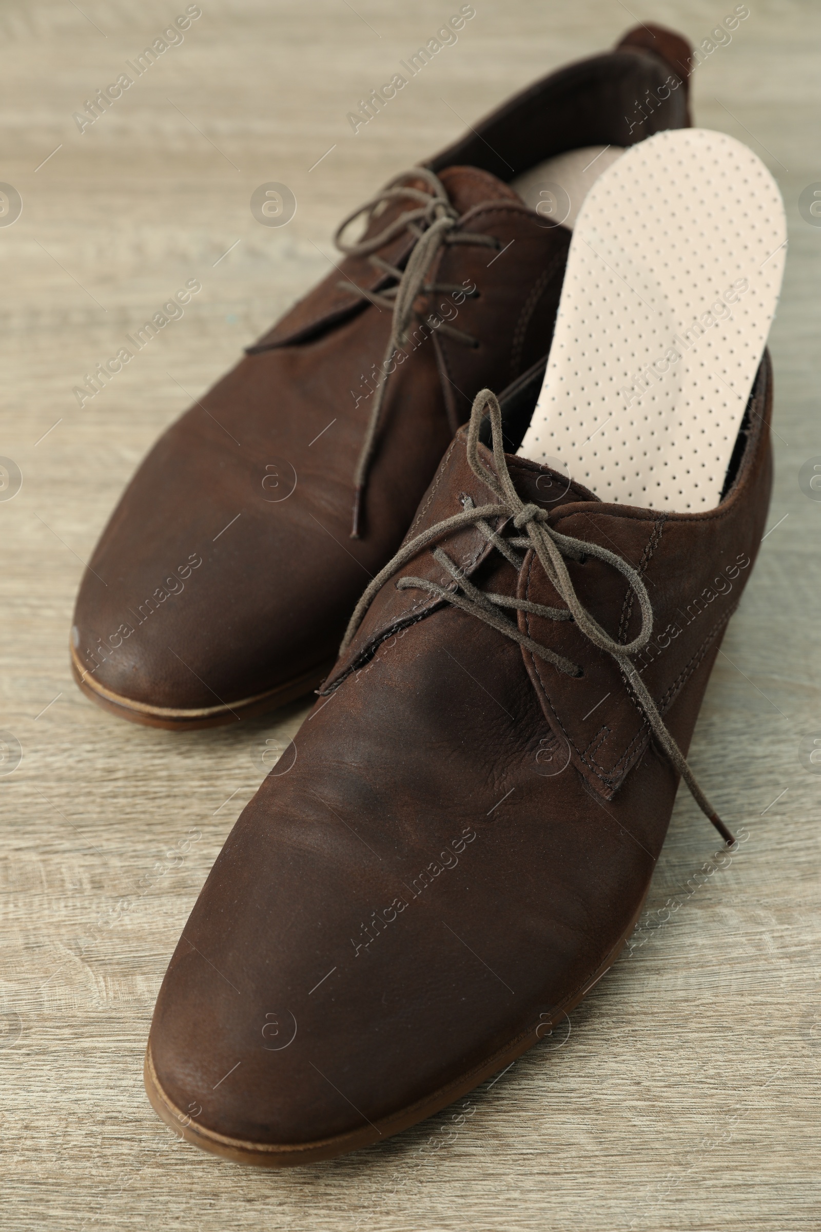 Photo of Orthopedic insoles in shoes on floor at home, closeup