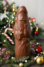 Chocolate Santa Claus and decorations near Christmas tree, closeup