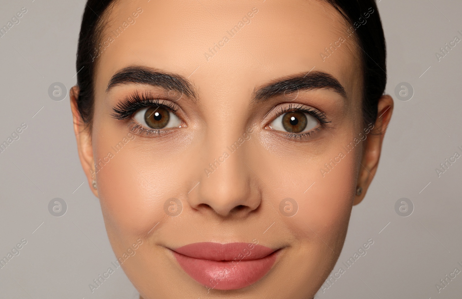 Photo of Beautiful young woman showing extended and ordinary eyelashes on grey background, closeup