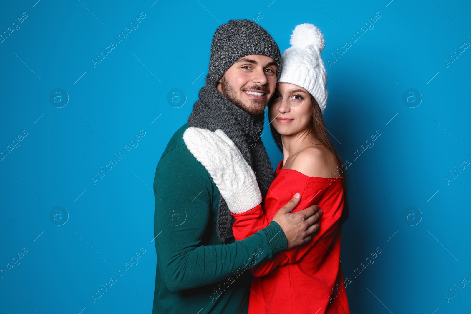 Photo of Young couple in warm clothes on color background. Christmas celebration