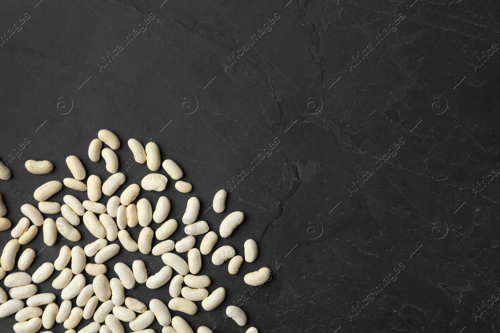 Photo of Raw beans and space for text on black background, flat lay. Vegetable seeds