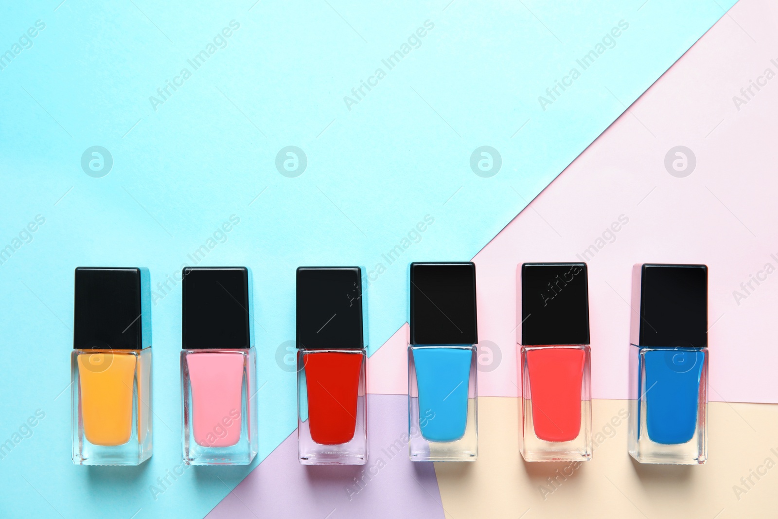 Photo of Bottles of nail polish on color background, top view with space for text