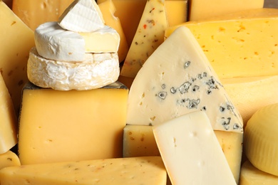 Different types of delicious cheese as background, closeup