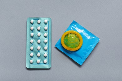 Photo of Condoms and birth control pills on light grey background, flat lay. Choosing method of contraception