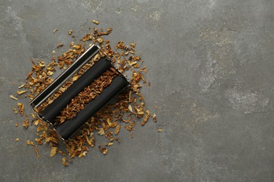 Photo of Roller with tobacco on dark grey table, top view and space for text. Making hand rolled cigarette