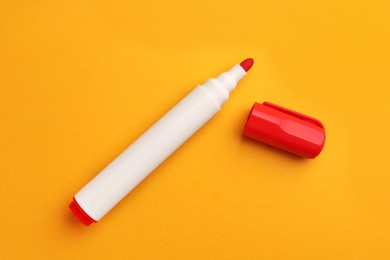 Photo of Bright red marker on orange background, flat lay