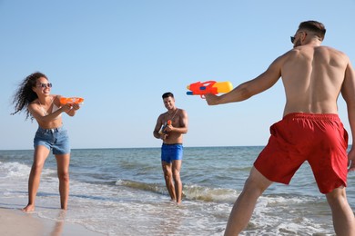 Friends with water guns having fun on beach