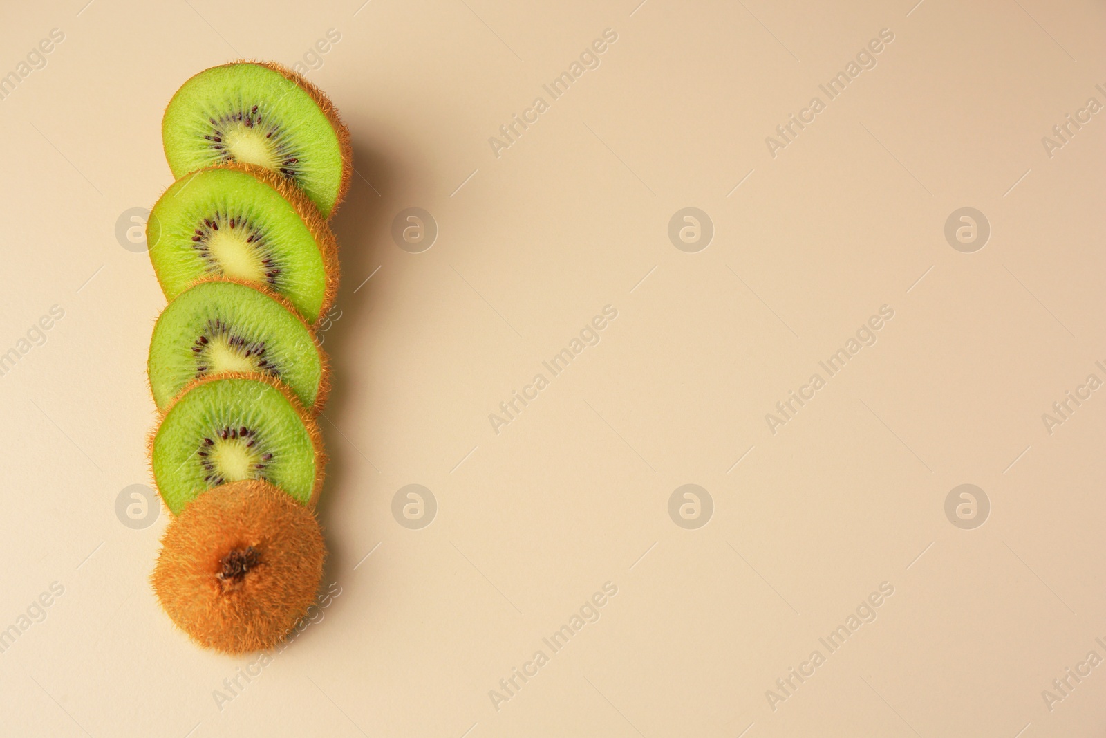 Photo of Sliced fresh kiwi on beige background, flat lay. Space for text