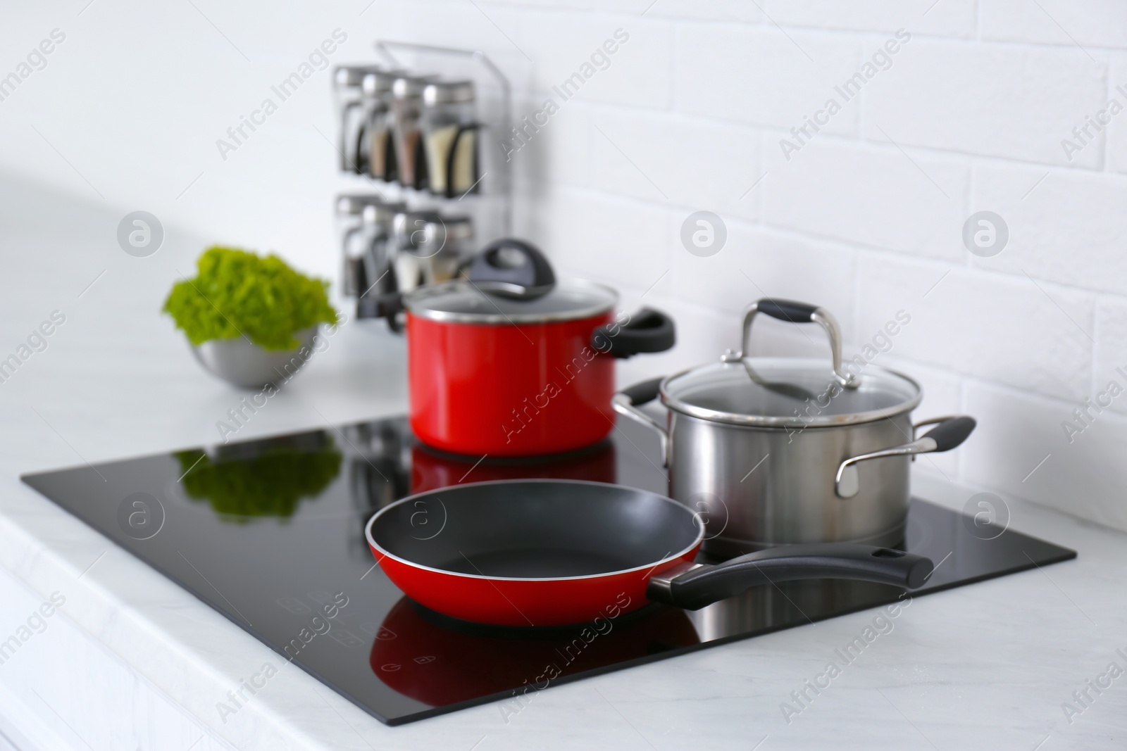 Photo of Saucepots and frying pan on induction stove in kitchen