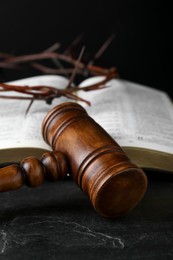 Photo of Judge gavel, bible and crown of thorns on black table