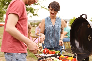 Photo of Young people having barbecue with modern grill outdoors