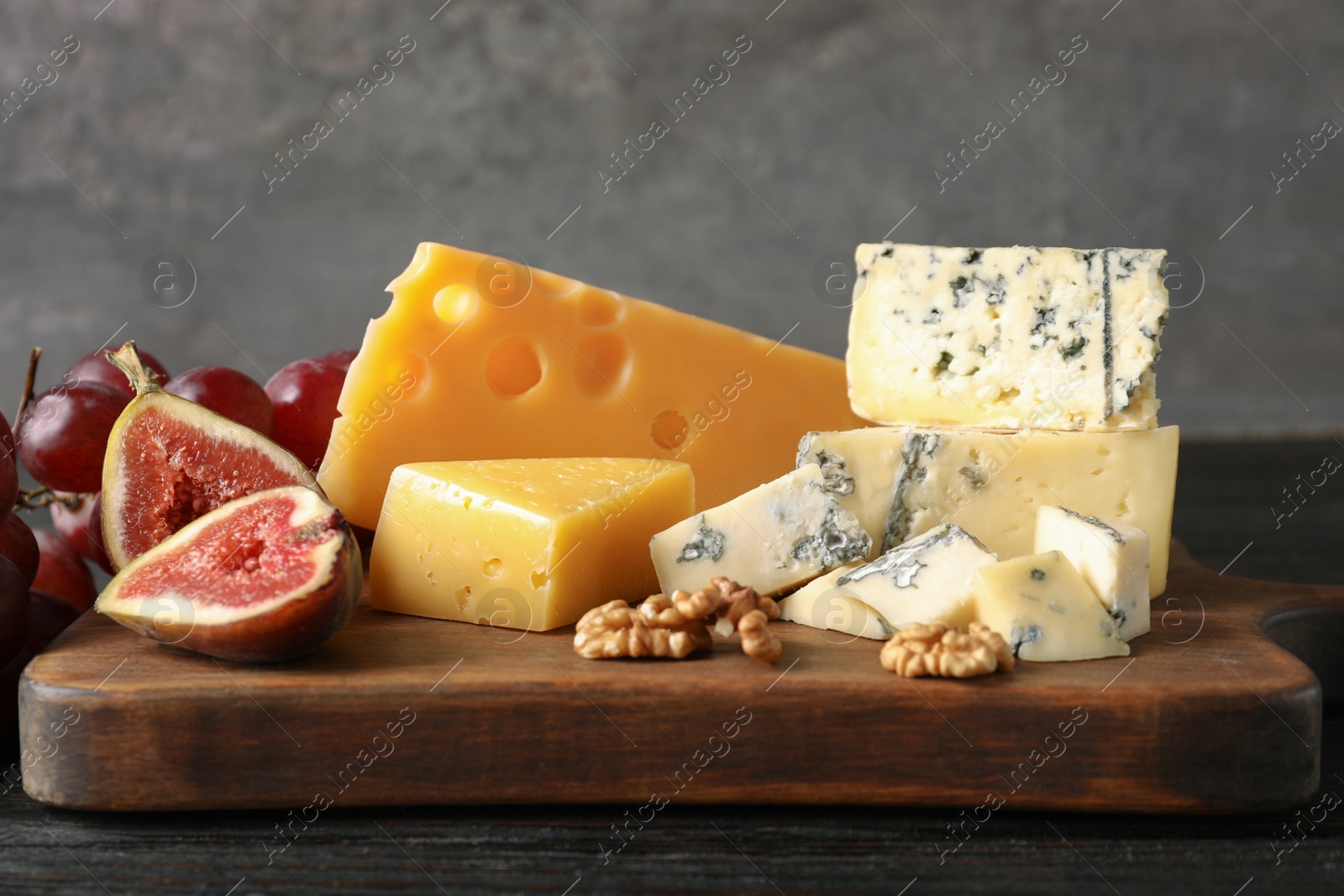 Photo of Different delicious cheeses served on wooden board