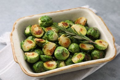 Photo of Delicious roasted Brussels sprouts and rosemary in baking dish on grey table