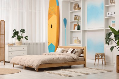 SUP board, bed and furniture in room. Interior design