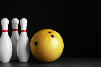 Yellow bowling ball and pins on black stone table