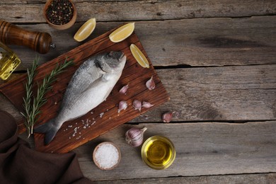 Photo of Flat lay composition with raw dorado fish and spices on wooden table. Space for text