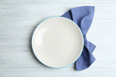 Photo of Empty plate and napkin on white wooden table, flat lay