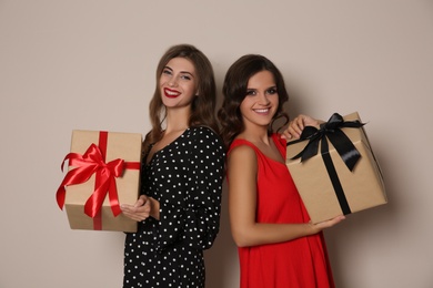 Happy women with gift boxes on beige background. Christmas party
