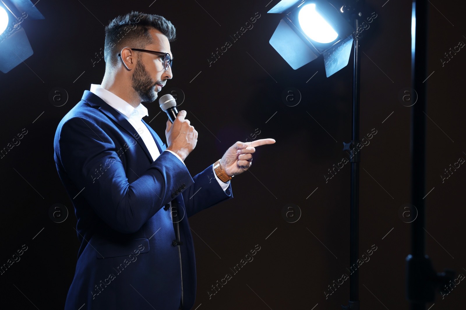 Photo of Motivational speaker with microphone performing on stage. Space for text