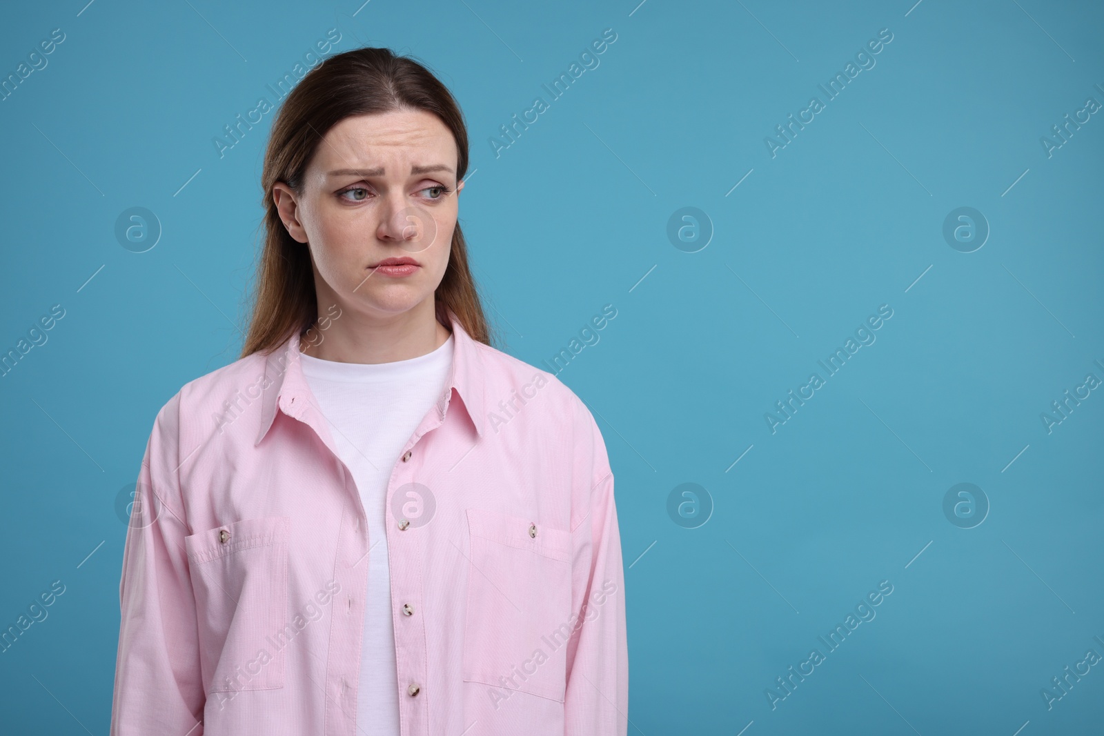 Photo of Portrait of sad woman on light blue background, space for text