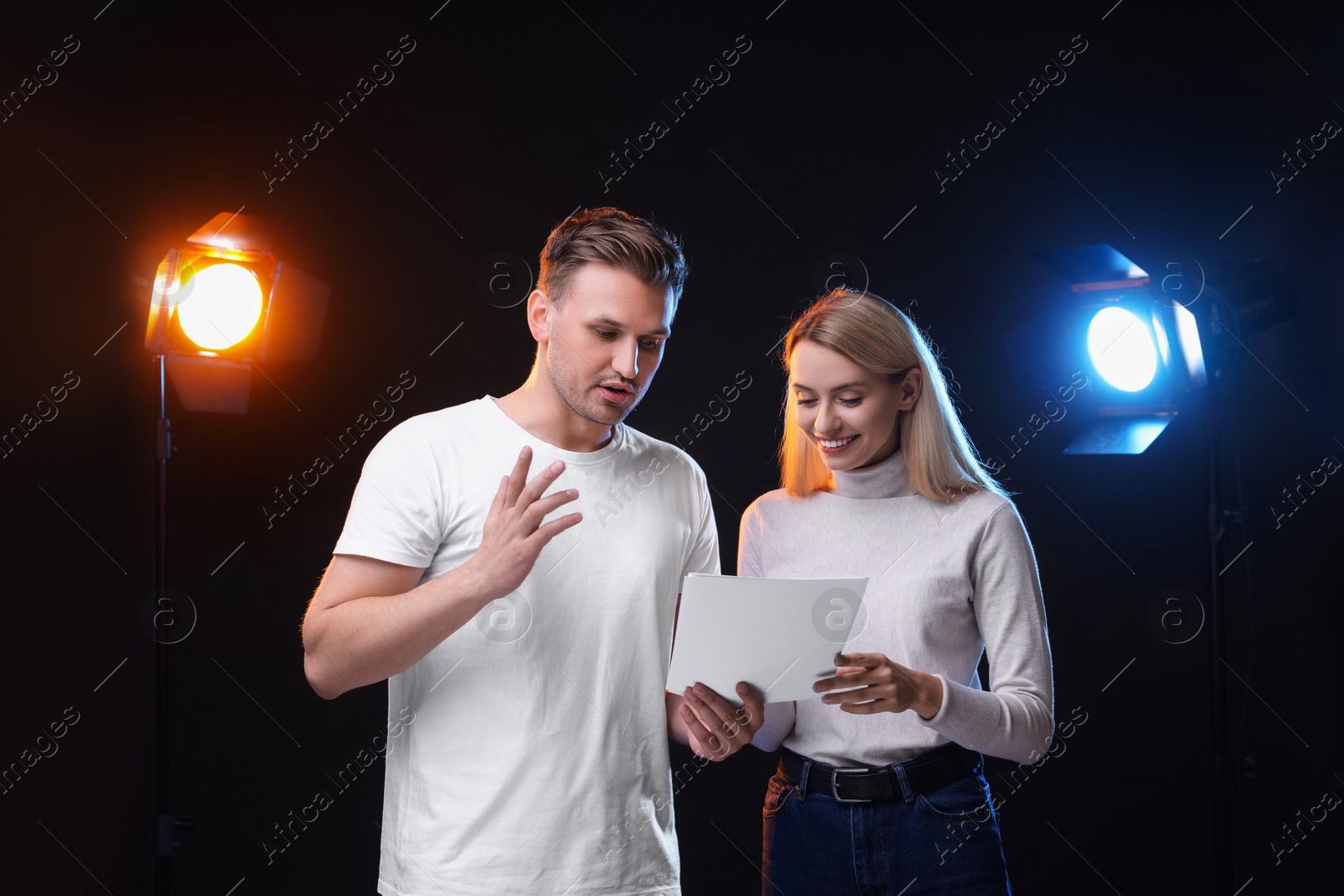 Photo of Casting call. Emotional woman and man with script performing on black background