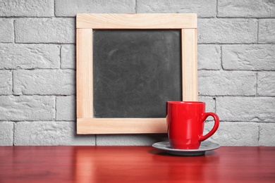 Photo of Ceramic cup on table near small chalkboard