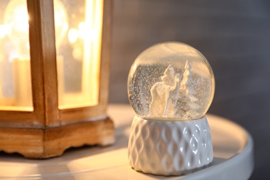 Snow globe with Christmas trees and deer on white table